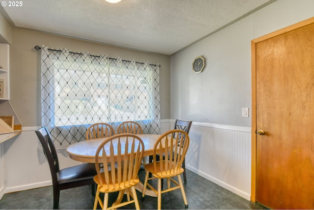 dining room featuring a wainscoted wall and a textured ceiling