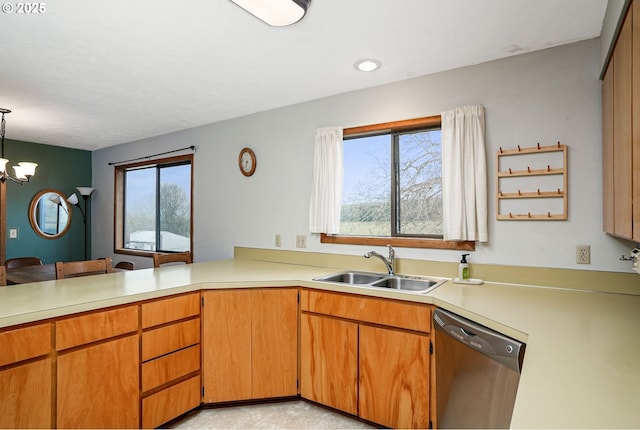 kitchen with a sink, an inviting chandelier, light countertops, and stainless steel dishwasher