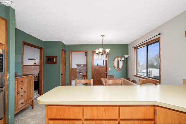 kitchen with light countertops, stainless steel microwave, decorative light fixtures, and a notable chandelier