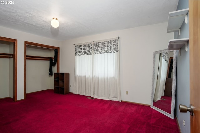 unfurnished bedroom with carpet floors, a textured ceiling, visible vents, and two closets