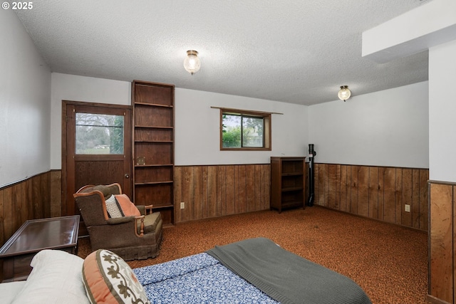 sitting room with a textured ceiling, wood walls, and wainscoting