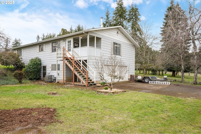 view of front of property featuring aphalt driveway, stairway, central AC unit, a front yard, and a garage