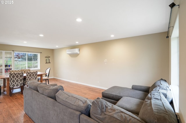 living room with light wood finished floors, recessed lighting, baseboards, and a wall mounted AC