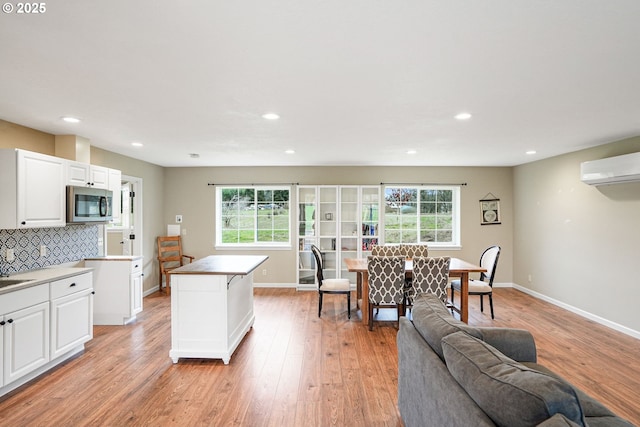 kitchen featuring light wood-style floors, tasteful backsplash, stainless steel microwave, and a wealth of natural light