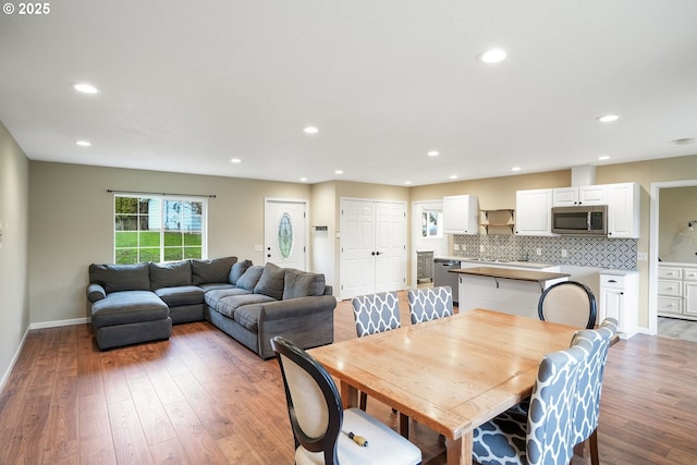 dining space with baseboards, light wood finished floors, and recessed lighting