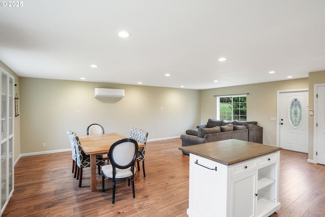 dining room with light wood-type flooring, baseboards, an AC wall unit, and recessed lighting