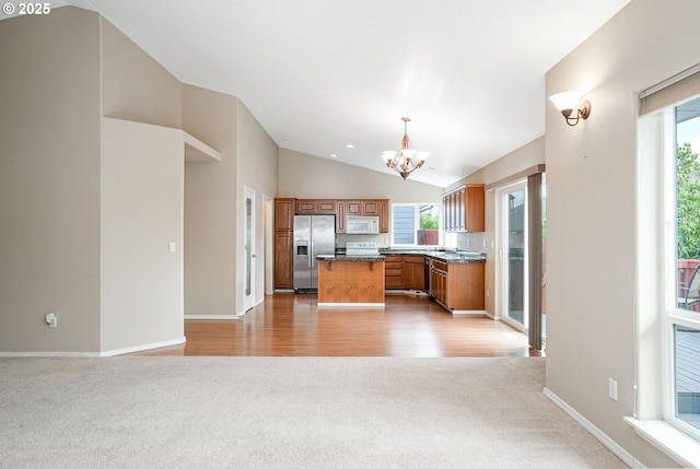 967 Whippoorwill Ct NW, Salem, OR 97304 - kitchen with stainless steel fridge, white microwave, light carpet, a chandelier, and vaulted ceiling