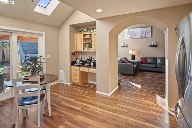 interior space featuring lofted ceiling with skylight, stainless steel fridge, light hardwood / wood-style flooring, and light brown cabinets