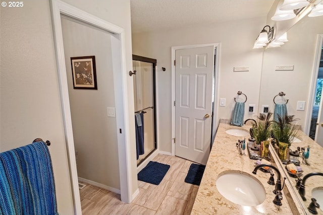 bathroom with vanity, an enclosed shower, and a textured ceiling