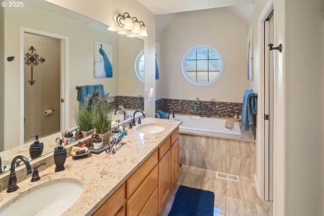 bathroom featuring vanity, tile patterned floors, lofted ceiling, and tiled bath