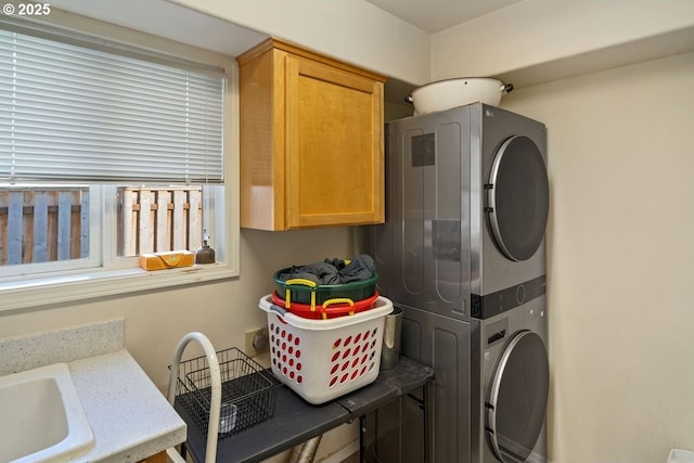 clothes washing area featuring cabinets, stacked washer and clothes dryer, and sink