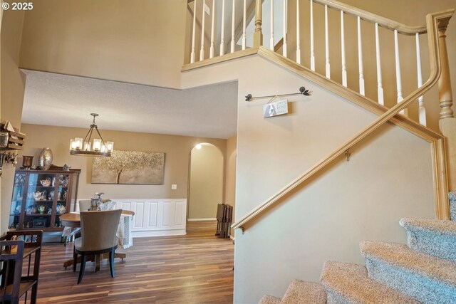 staircase with hardwood / wood-style floors, a notable chandelier, and a towering ceiling