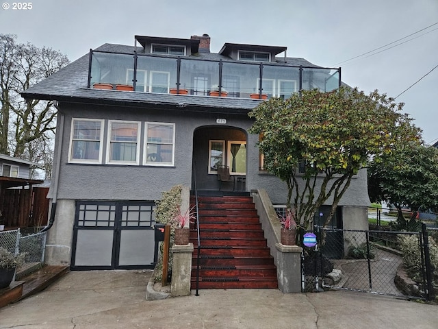 view of front of property with driveway, a garage, a balcony, fence, and stucco siding