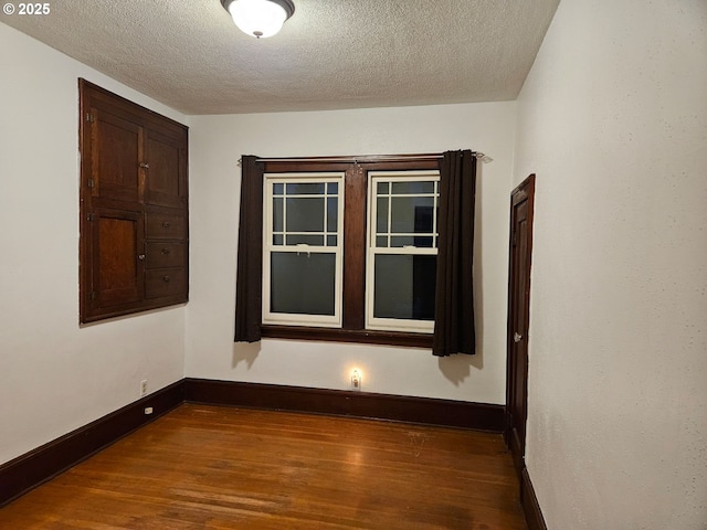 empty room with dark wood-type flooring and a textured ceiling