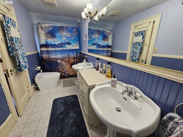 bathroom featuring visible vents, toilet, wainscoting, a sink, and tile patterned floors