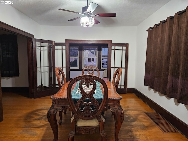 dining area with baseboards, a textured ceiling, visible vents, and wood finished floors