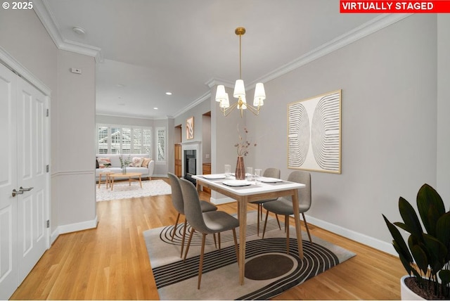 dining area with hardwood / wood-style flooring, an inviting chandelier, and ornamental molding