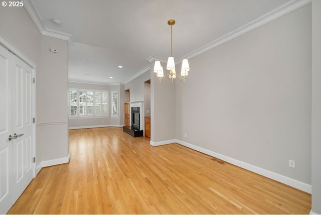 unfurnished living room featuring light hardwood / wood-style floors, a notable chandelier, and ornamental molding