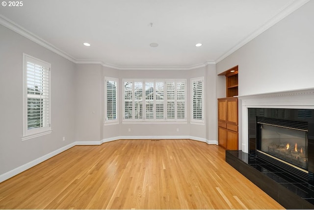 unfurnished living room featuring a tile fireplace, light hardwood / wood-style flooring, and ornamental molding