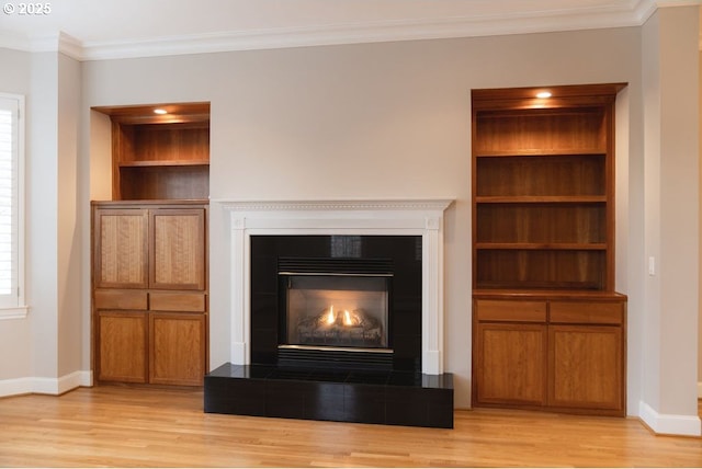 interior details with hardwood / wood-style flooring, crown molding, and a tiled fireplace