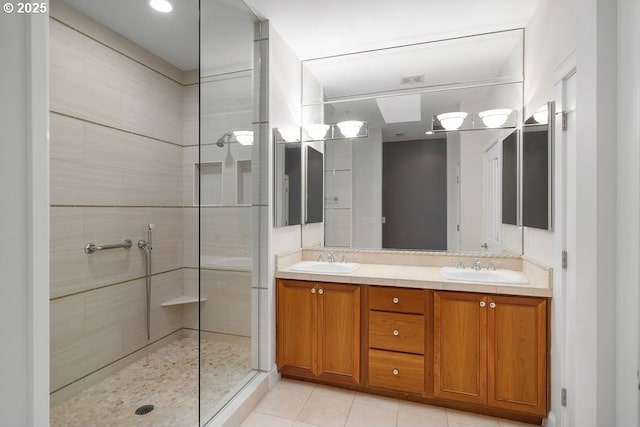 bathroom with tile patterned flooring, vanity, and tiled shower