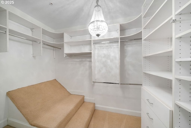 walk in closet with a notable chandelier and light colored carpet