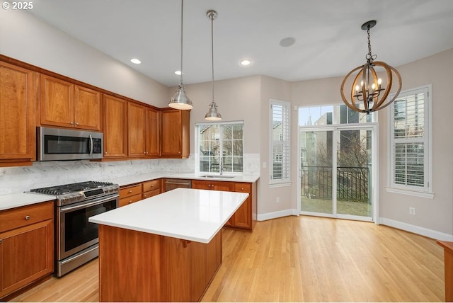 kitchen featuring sink, hanging light fixtures, a chandelier, a kitchen island, and appliances with stainless steel finishes