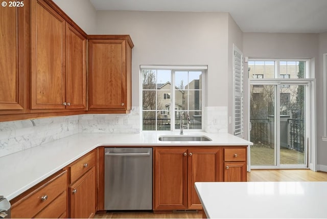 kitchen with dishwasher, light wood-type flooring, tasteful backsplash, and sink