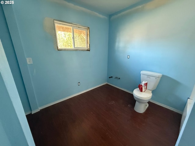 bathroom with toilet, baseboards, and wood finished floors