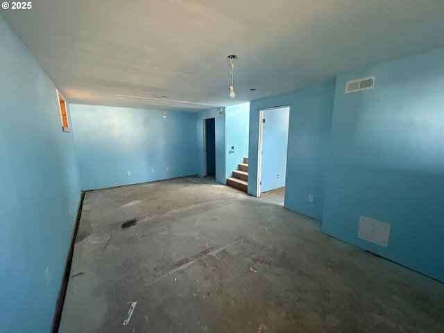 unfurnished room with stairs, visible vents, and unfinished concrete flooring