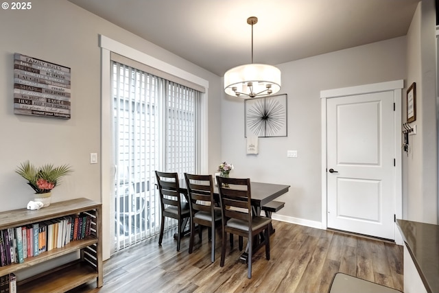 dining space with a chandelier, wood finished floors, and baseboards