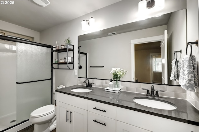 bathroom with a stall shower, toilet, and double vanity