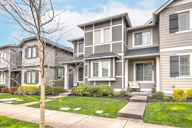townhome / multi-family property with a front lawn, stucco siding, and roof with shingles