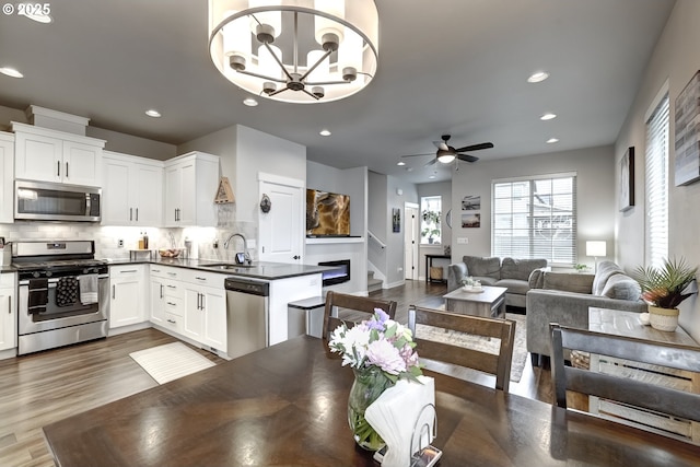 dining room with dark wood-style flooring, ceiling fan, recessed lighting, a chandelier, and stairs