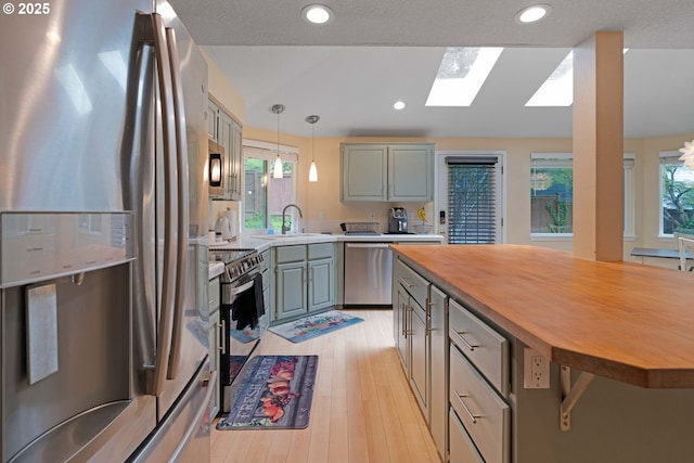 13465 SW Lancewood St, Beaverton, OR 97008 - kitchen featuring appliances with stainless steel finishes, wood counters, a skylight, light wood-type flooring, and recessed lighting