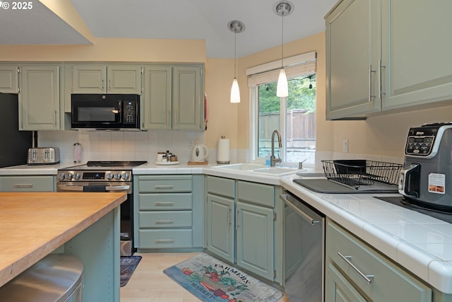 13465 SW Lancewood St, Beaverton, OR 97008 - kitchen featuring stainless steel appliances, a sink, decorative backsplash, hanging light fixtures, and tile counters