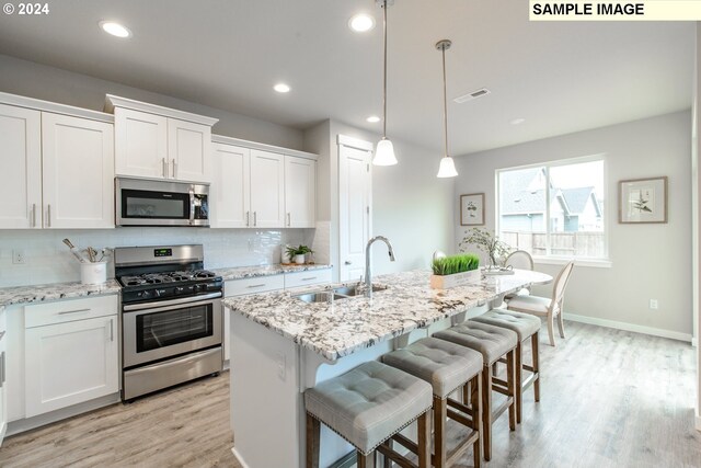 kitchen featuring white cabinets, visible vents, stainless steel appliances, a sink, and backsplash