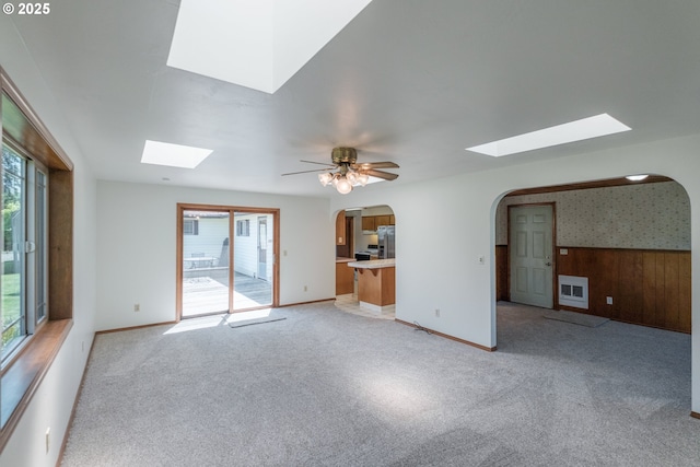 30563 Fairview Rd, Lebanon, OR 97355 - unfurnished living room with a skylight, arched walkways, light colored carpet, ceiling fan, and baseboards