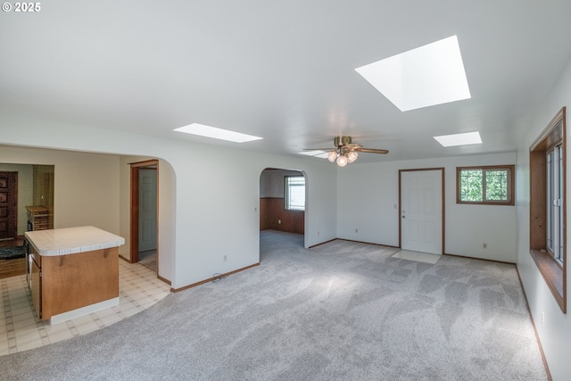 30563 Fairview Rd, Lebanon, OR 97355 - unfurnished living room featuring a skylight, arched walkways, ceiling fan, light colored carpet, and baseboards