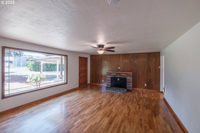 30563 Fairview Rd, Lebanon, OR 97355 - unfurnished living room with wood finished floors, a ceiling fan, a textured ceiling, baseboards, and wood walls