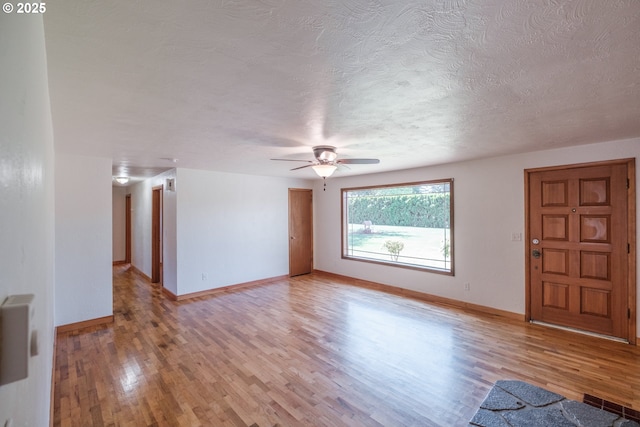 30563 Fairview Rd, Lebanon, OR 97355 - unfurnished living room featuring light wood finished floors, a ceiling fan, a textured ceiling, and baseboards