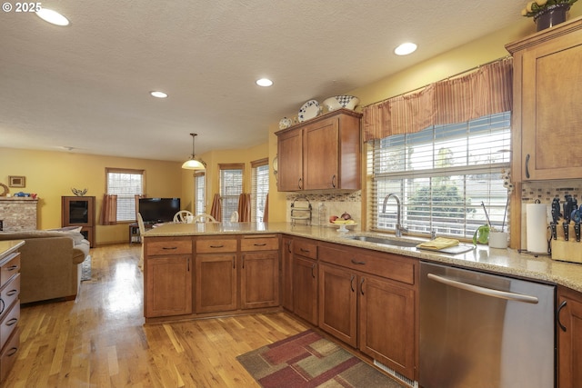 kitchen featuring brown cabinets, a sink, a peninsula, and stainless steel dishwasher