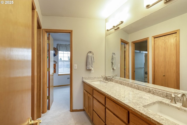 bathroom with double vanity, baseboards, an enclosed shower, and a sink