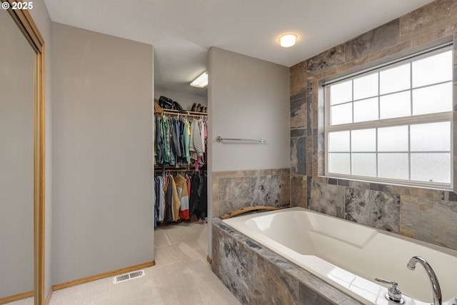 full bathroom with visible vents, a spacious closet, and a bath