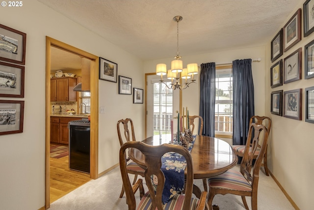 dining room with a textured ceiling, light wood finished floors, baseboards, and an inviting chandelier