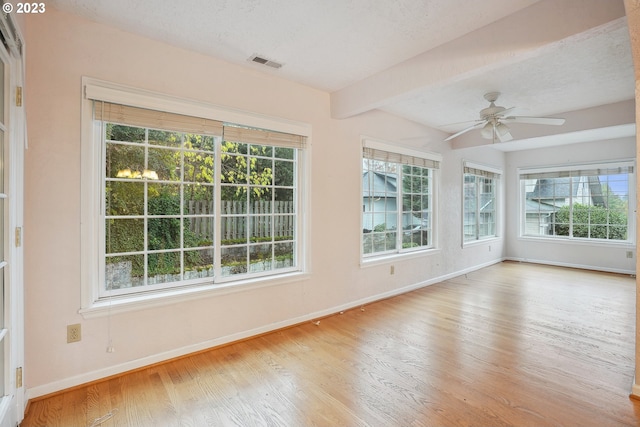 unfurnished sunroom featuring beamed ceiling and ceiling fan