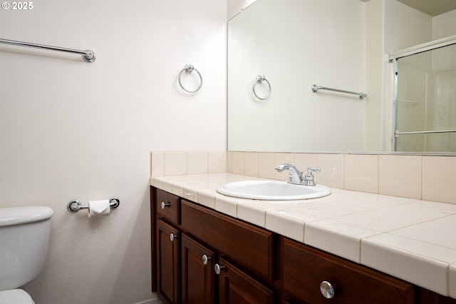 full bathroom featuring a shower with shower door, vanity, and toilet