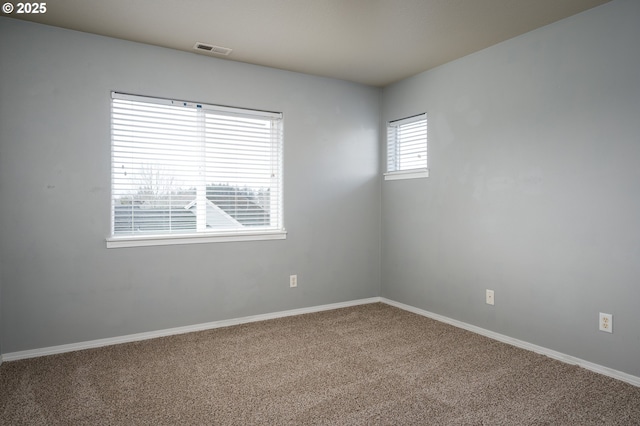 carpeted spare room featuring visible vents and baseboards