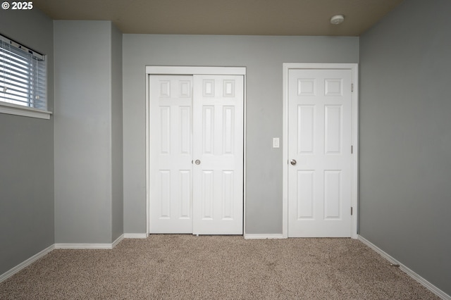 unfurnished bedroom with a closet, carpet, and baseboards