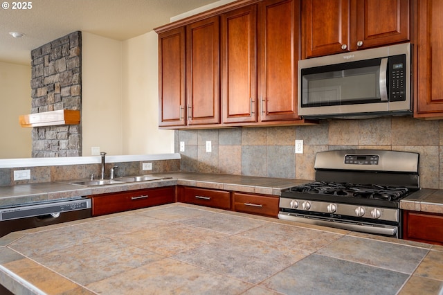 kitchen with stainless steel appliances, brown cabinetry, a sink, and backsplash